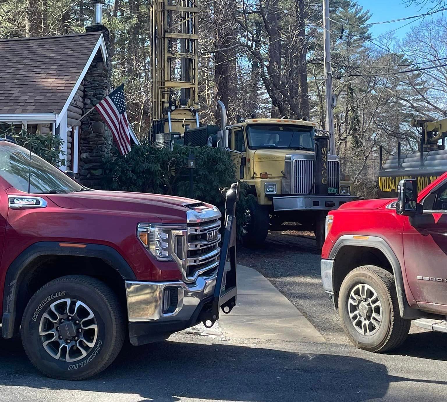 A red truck is parked next to a yellow truck during a well inspection