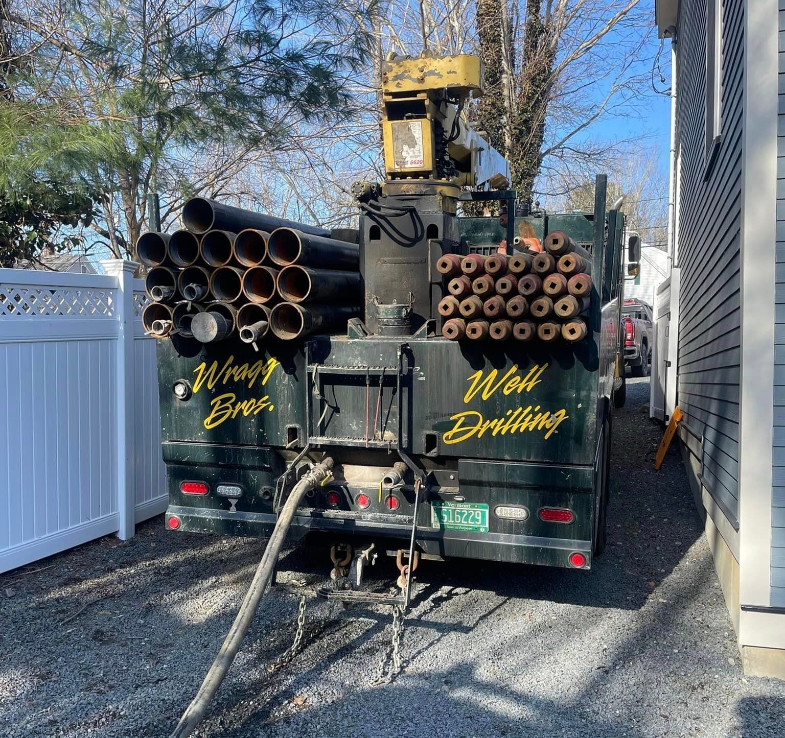 A truck is parked in a driveway next to a house for water well drilling