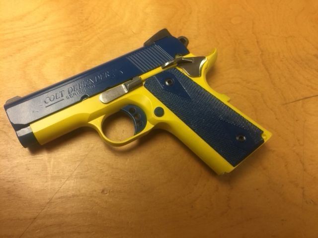 Yellow and blue handgun on a wooden surface