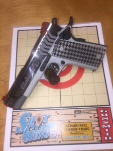 Toy pistol on a cardboard target game board with a red bullseye and patterned grip.