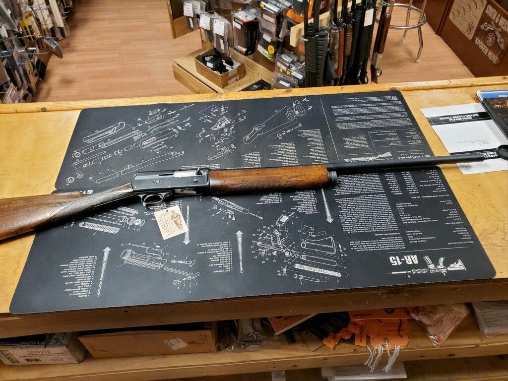 Shotgun displayed on a black mat atop a wooden table in a store.
