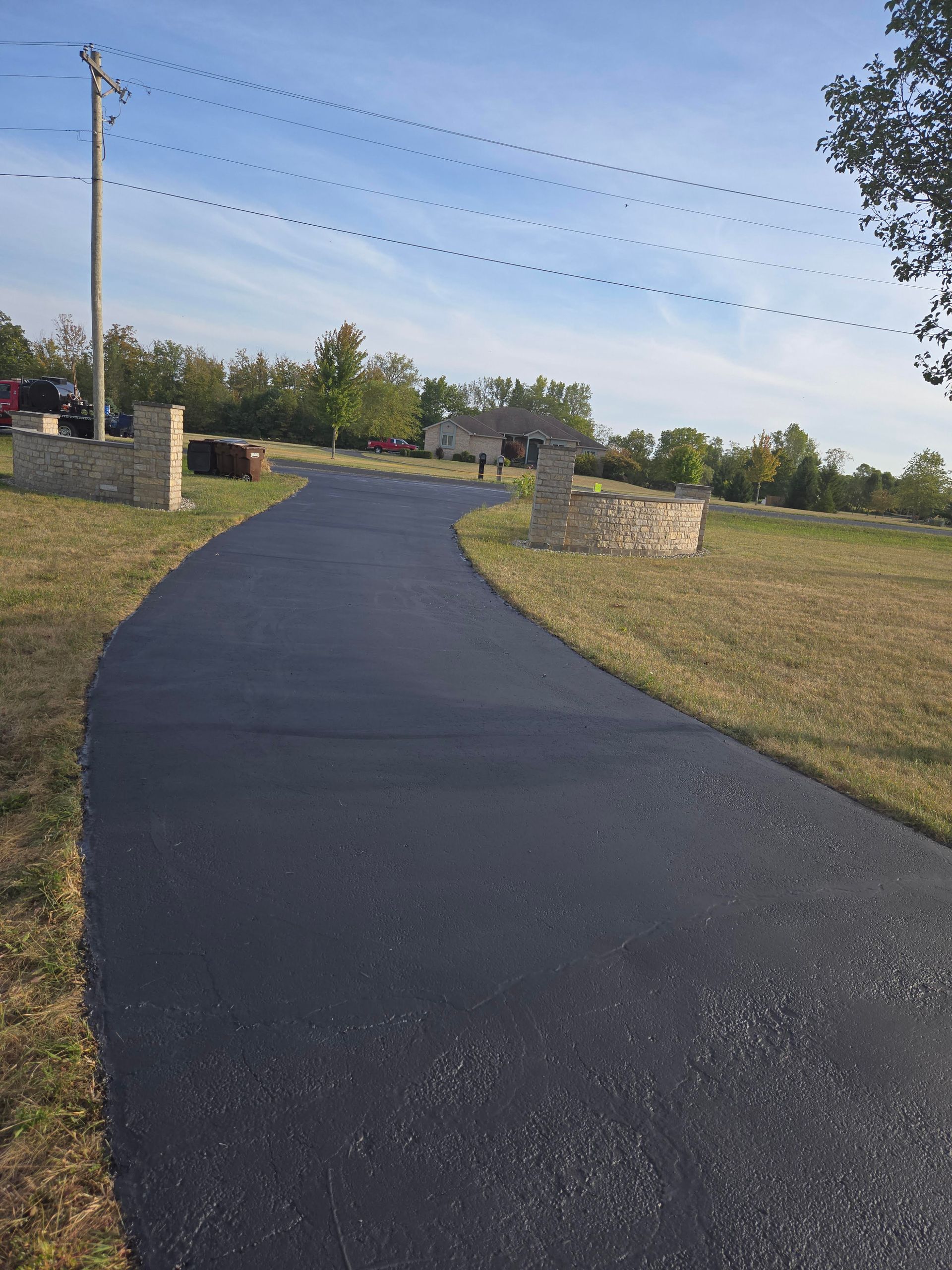A black asphalt road going through a grassy field.