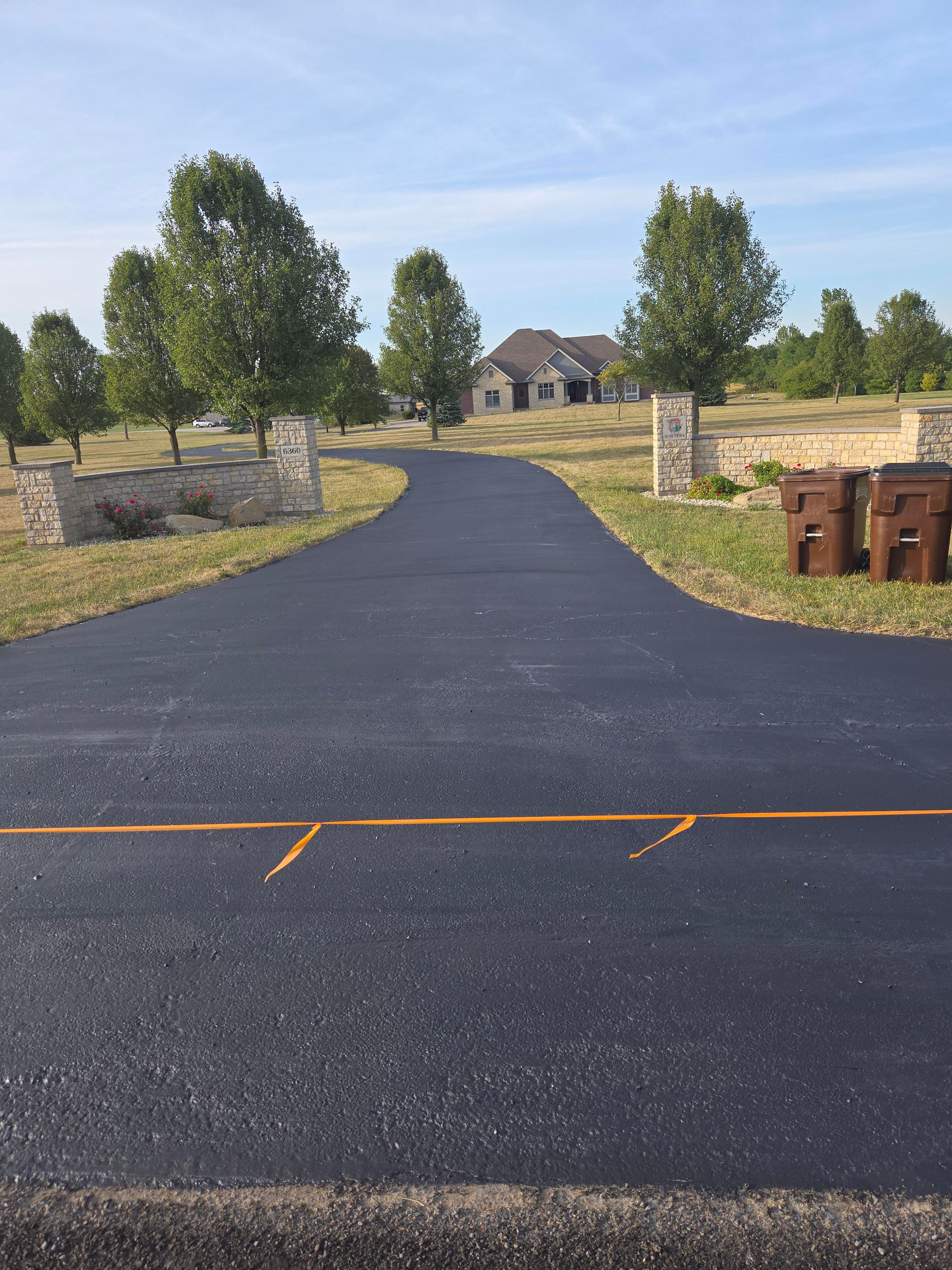 A driveway leading to a house with trees on both sides