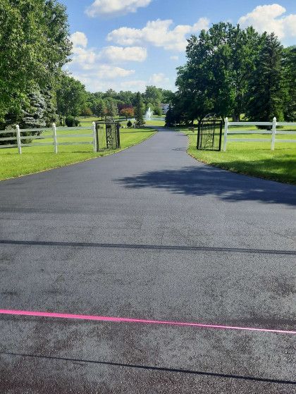 A black asphalt driveway with a pink line on the side of it.