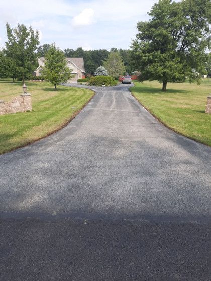 A driveway leading to a house with trees on both sides