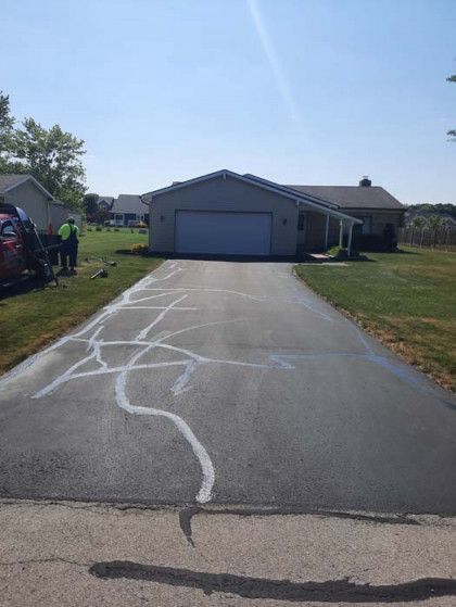A driveway with a garage and a house in the background.