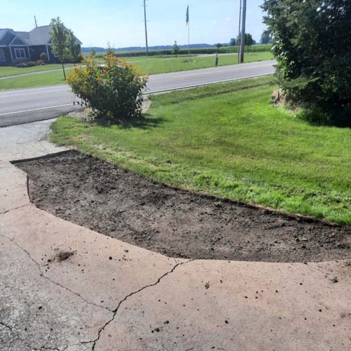 A concrete driveway with a grassy area in front of it