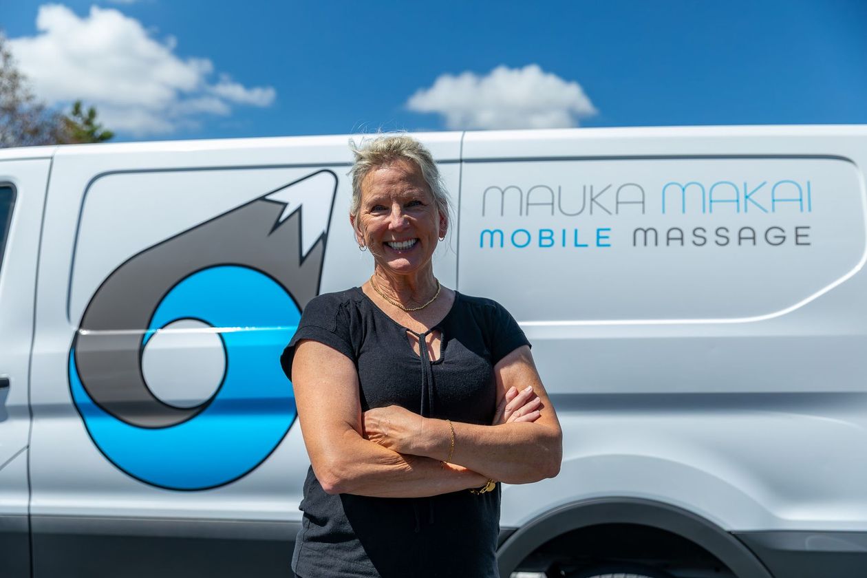 Two women giving back massages outdoors on a sunny day.
