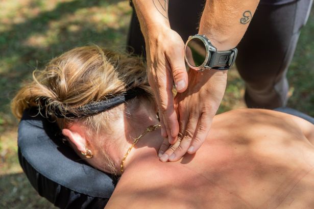 Person receiving a neck massage outdoors. Hands on the neck, watch on wrist.
