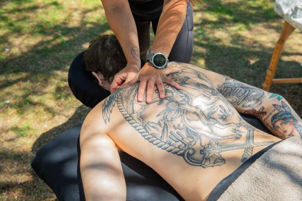 Person with back tattoos getting a massage outdoors.