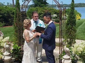 A bride and groom are getting married in front of a lake.