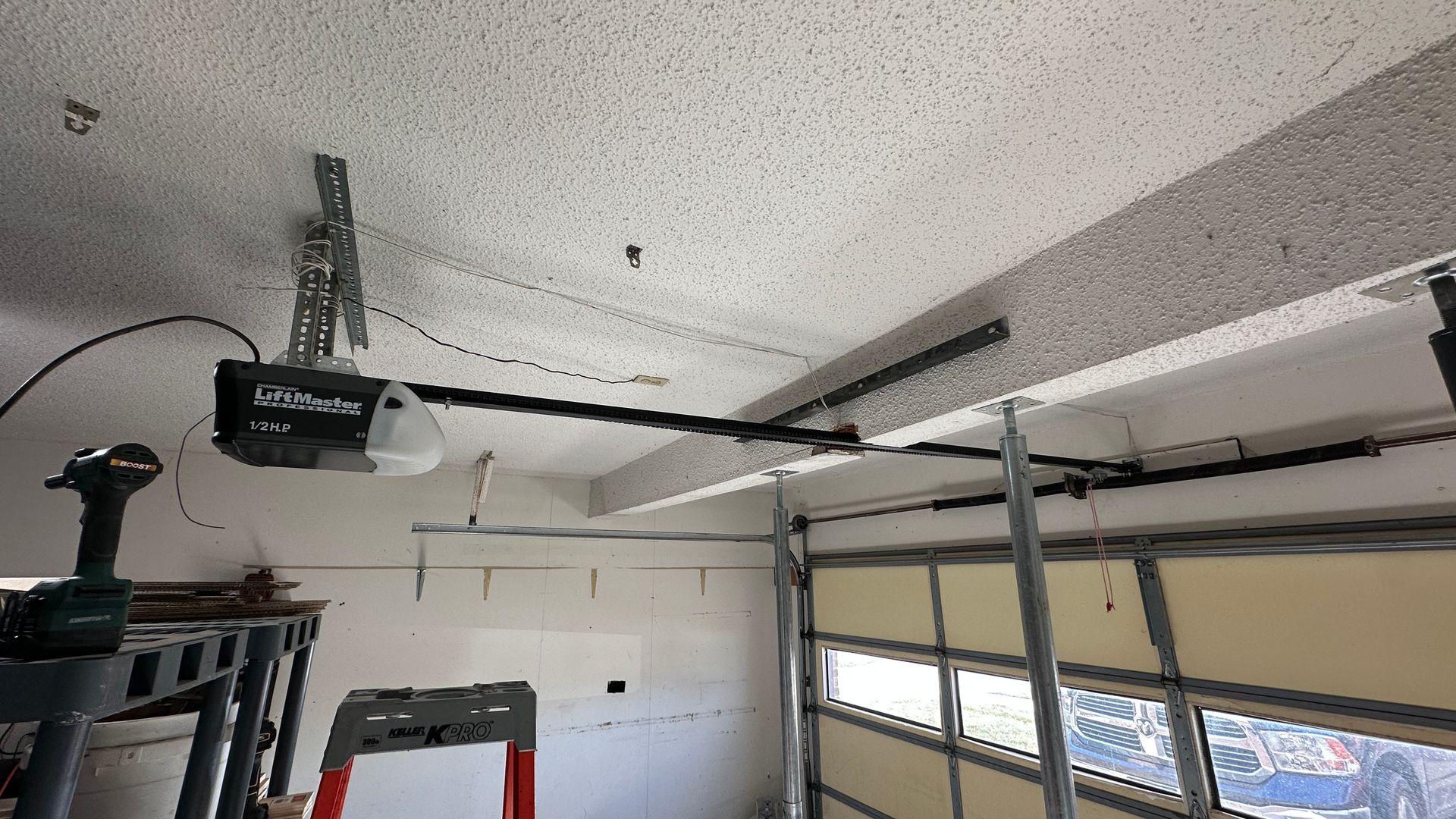 A two-story suburban house with brown vertical siding, stone accents, two white garage doors, and a front entrance.