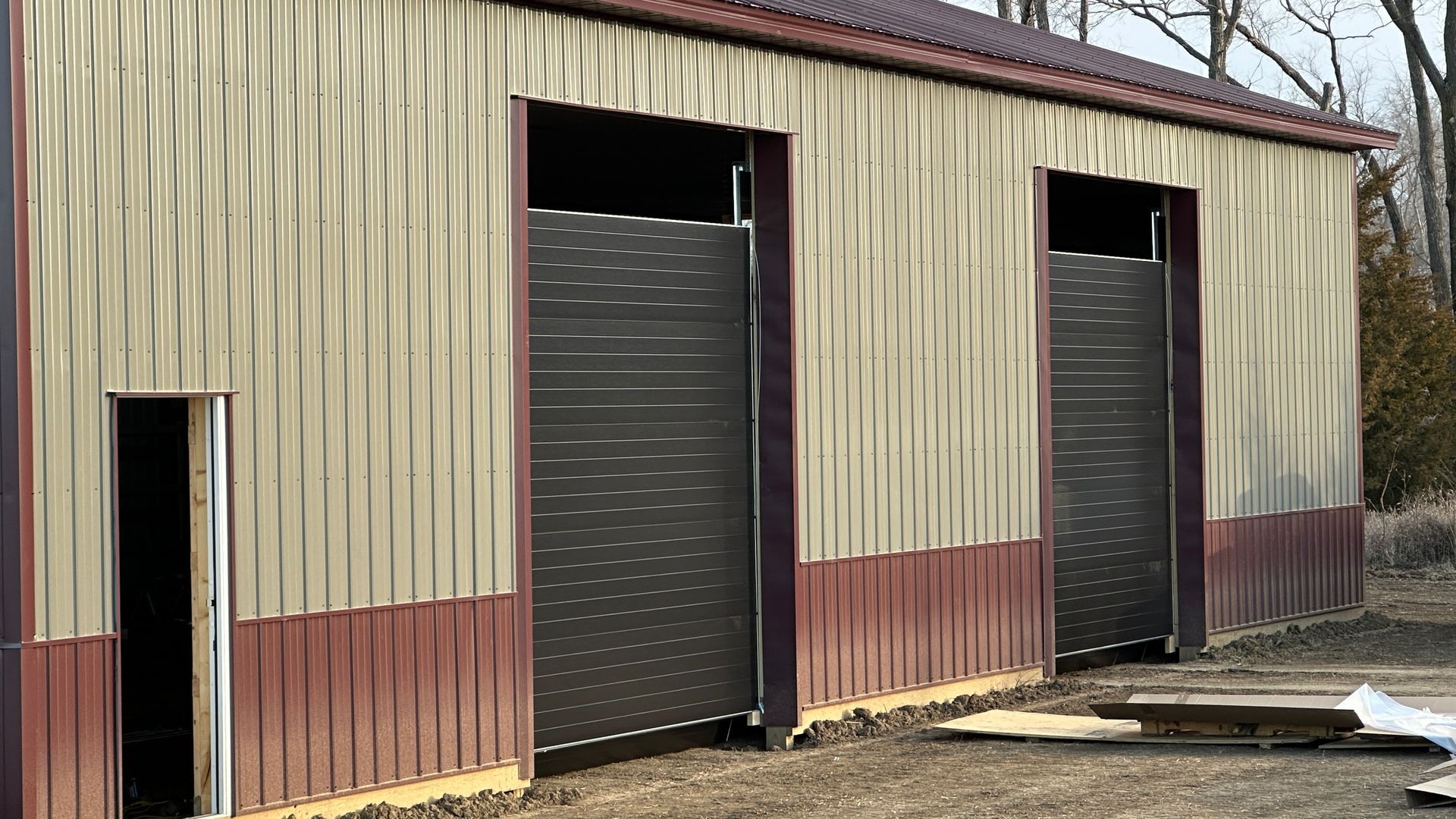 A row of dark grey, horizontal-slatted garage doors set into a building exterior with a paved driveway in front.
