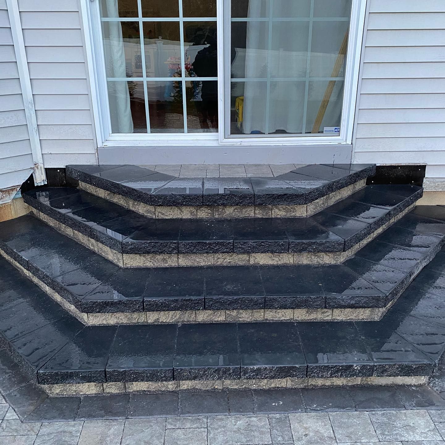 Stone steps leading up to a sliding glass door. Dark gray blocks, tan trim.
