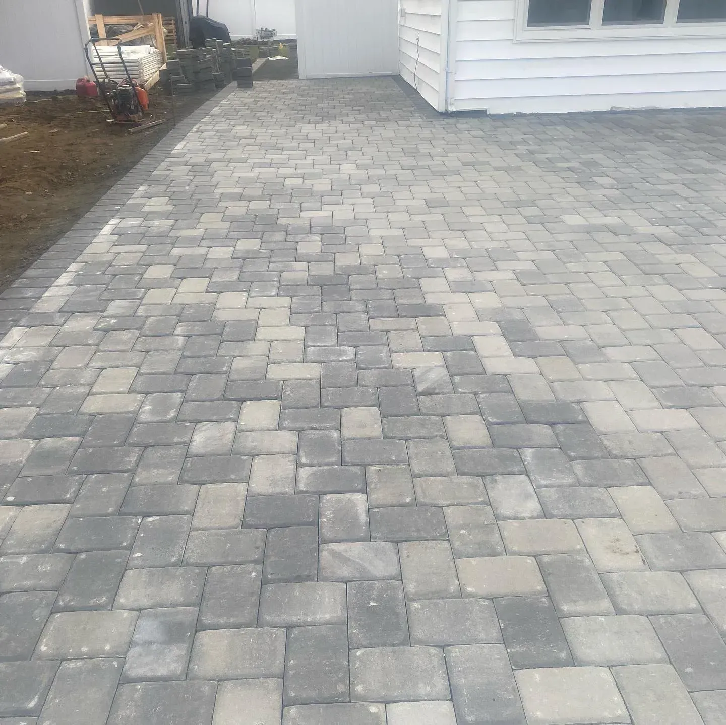 Brick driveway leading to a white building. The bricks are gray, brown, and beige.