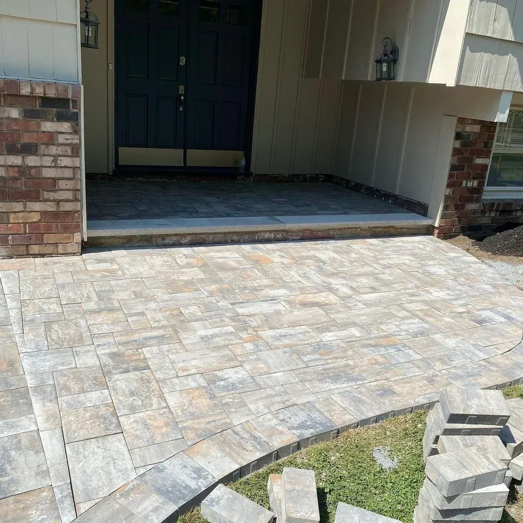 Brick entryway with paved walkway leading to a dark blue door.