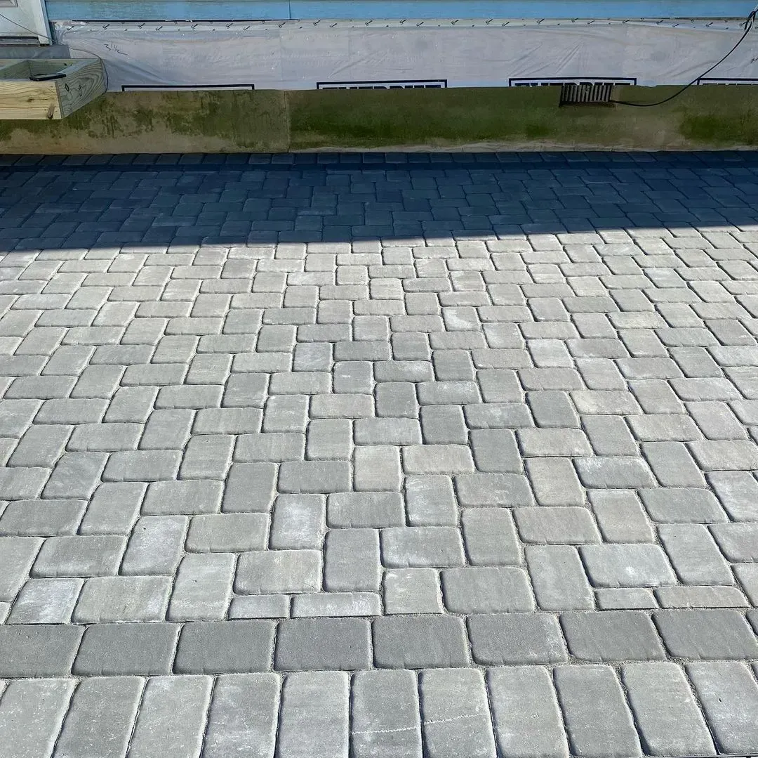 Gray brick pavers in herringbone pattern leading to a building's foundation.