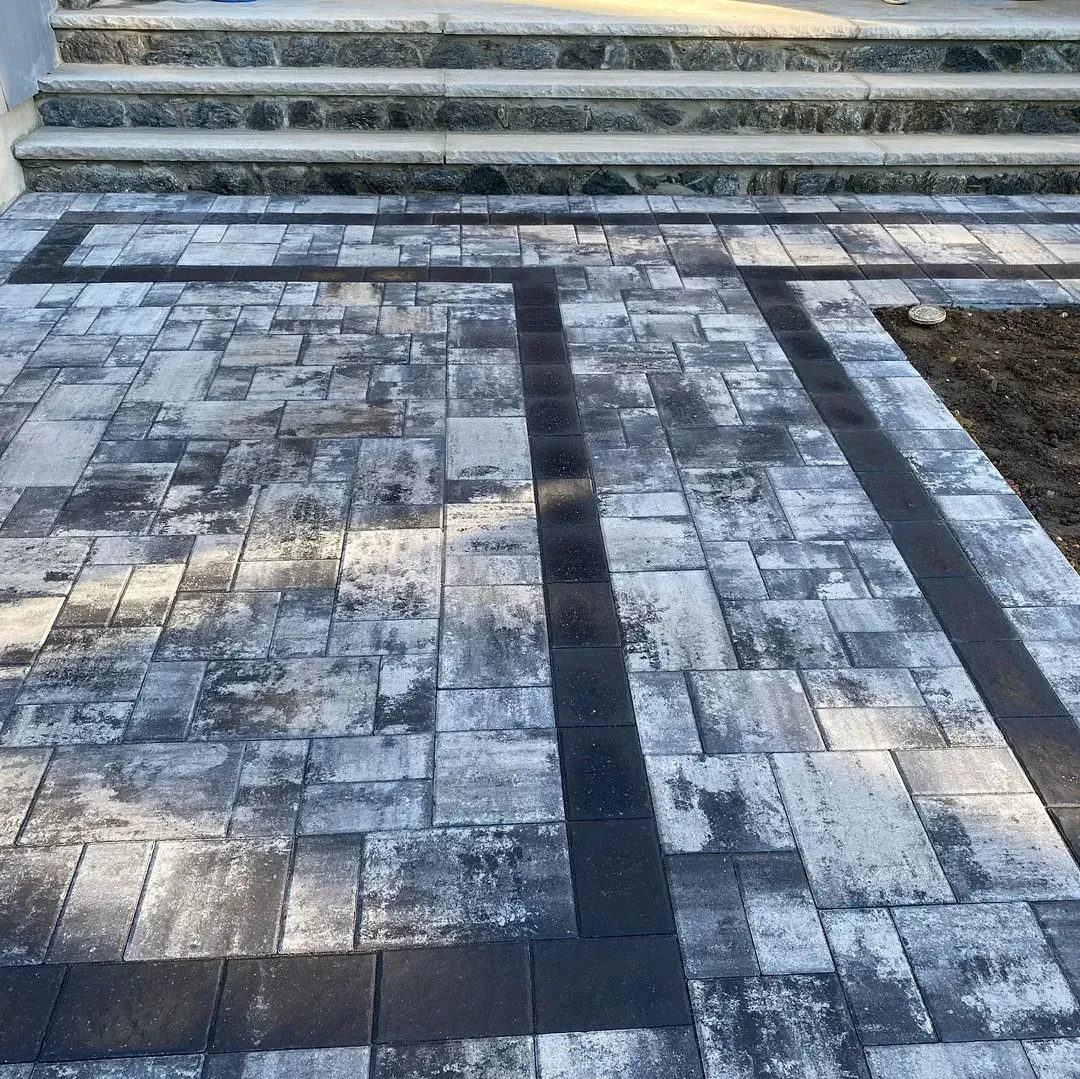 Patio with gray and black paving stones leading to stone steps.