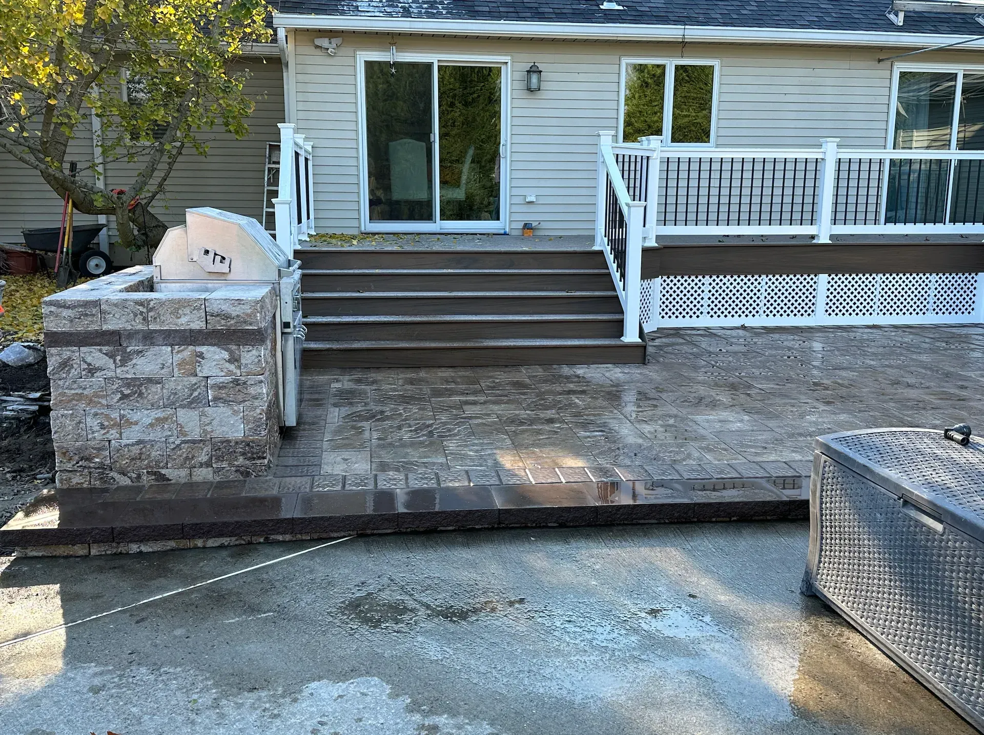 Backyard patio with stairs leading to a house with sliding glass doors and a built-in barbecue grill.