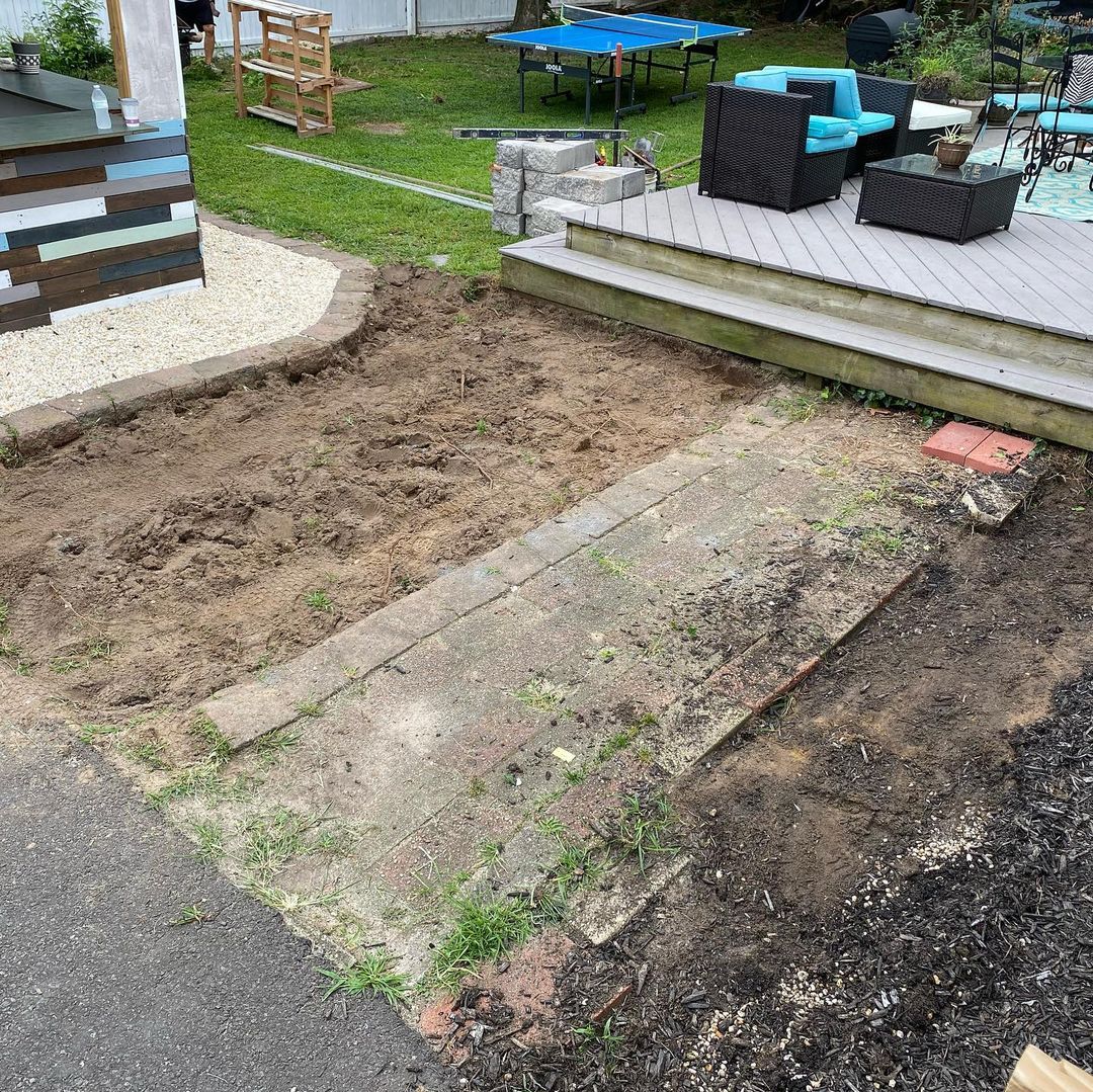 Brick driveway with a man by garage doors; a street and trees in the background.