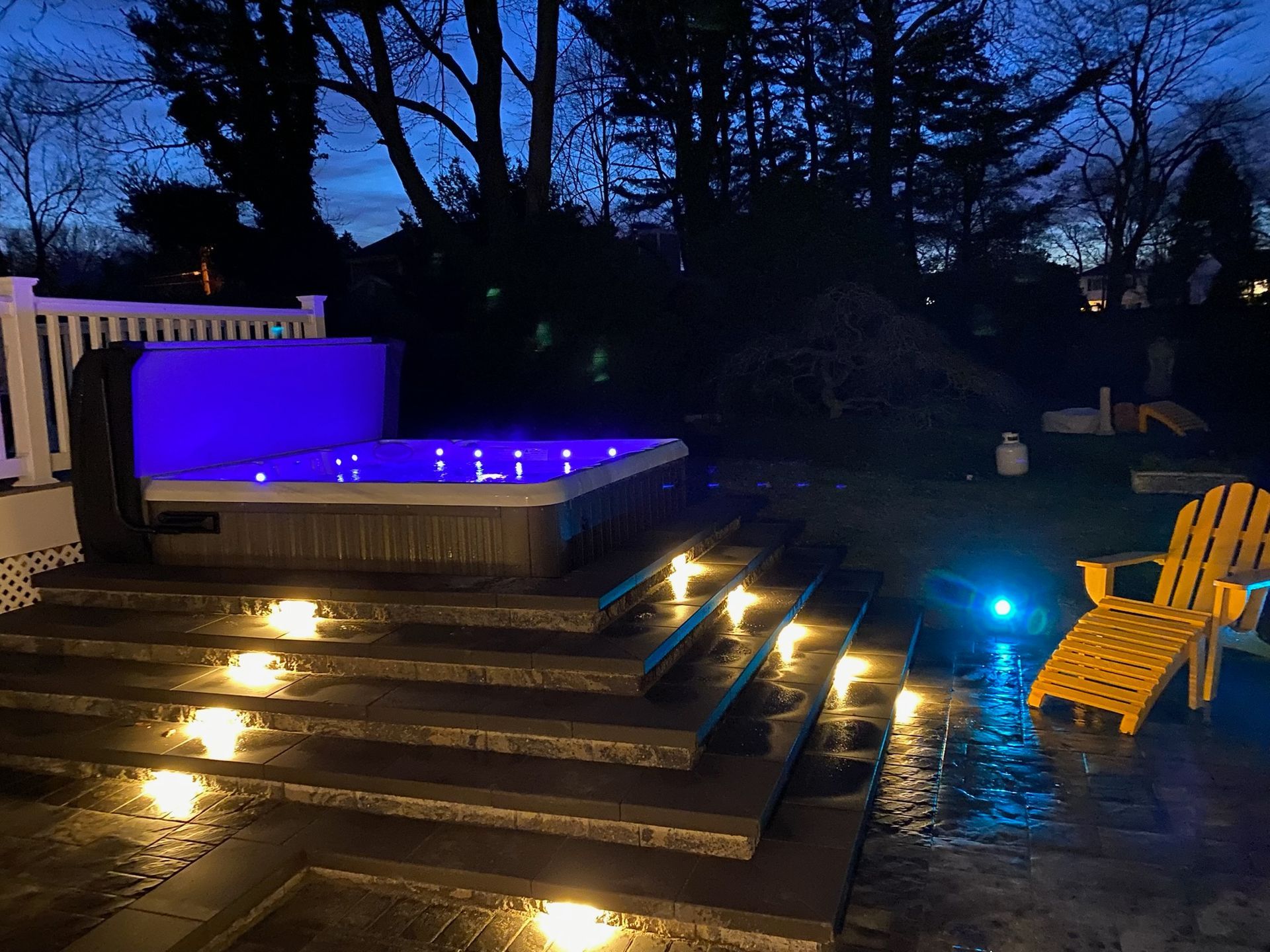 Two electricians working on an electrical panel outside a building. One holds a cable.