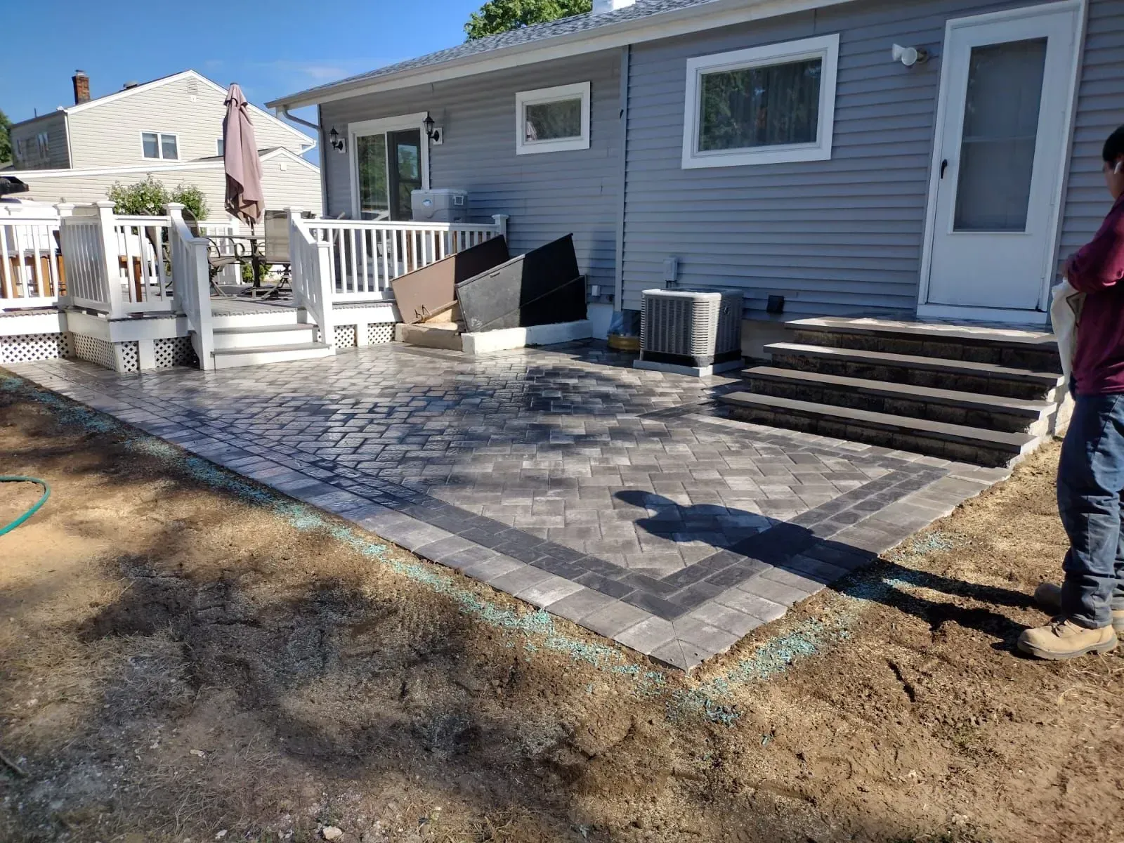 Backyard patio with brickwork, steps, and a partially visible house.