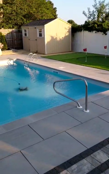 Trench dug in a grassy yard, leading to a house with black siding, and an electrical box.