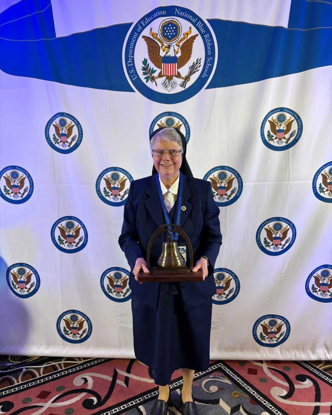 A woman is standing in front of a wall holding a trophy.