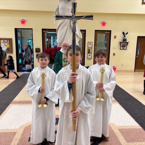 A group of children in white robes holding candles and a cross