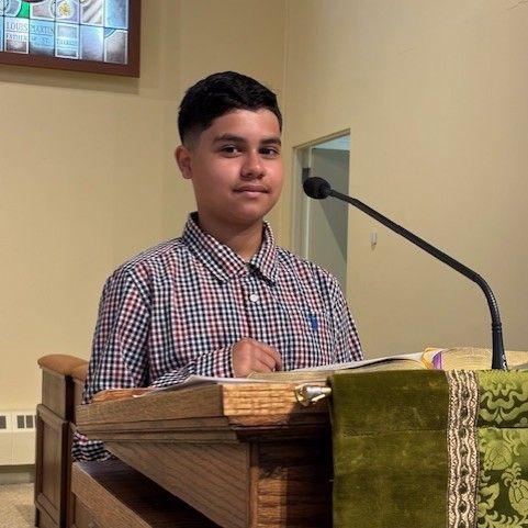A young man is sitting at a podium with a microphone.
