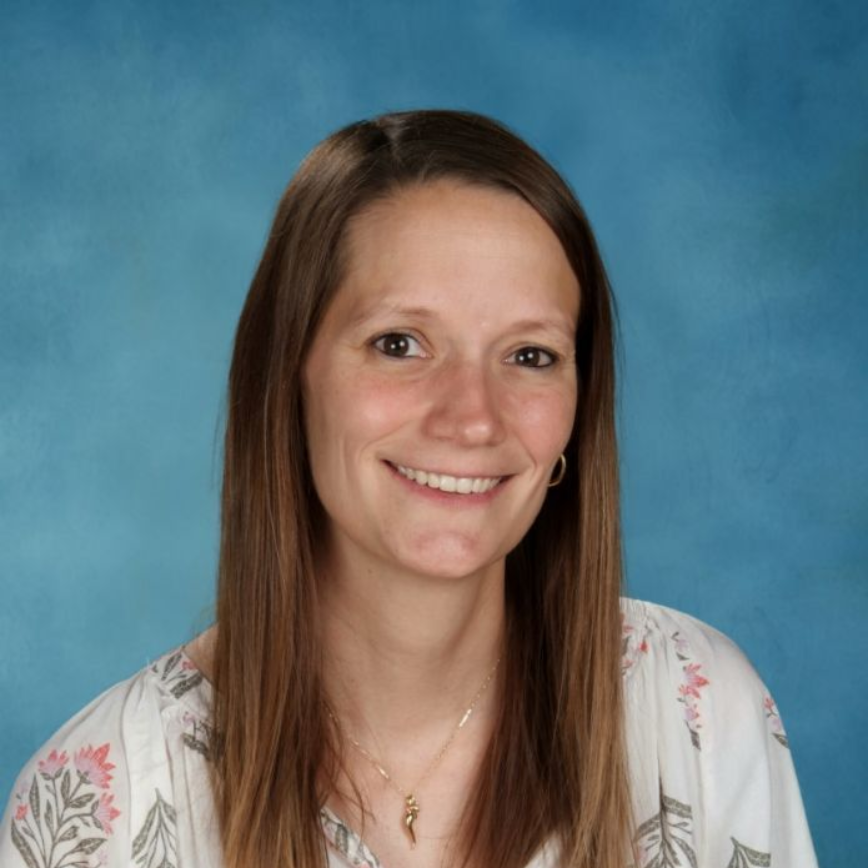 A woman is smiling for a picture in front of a blue background.