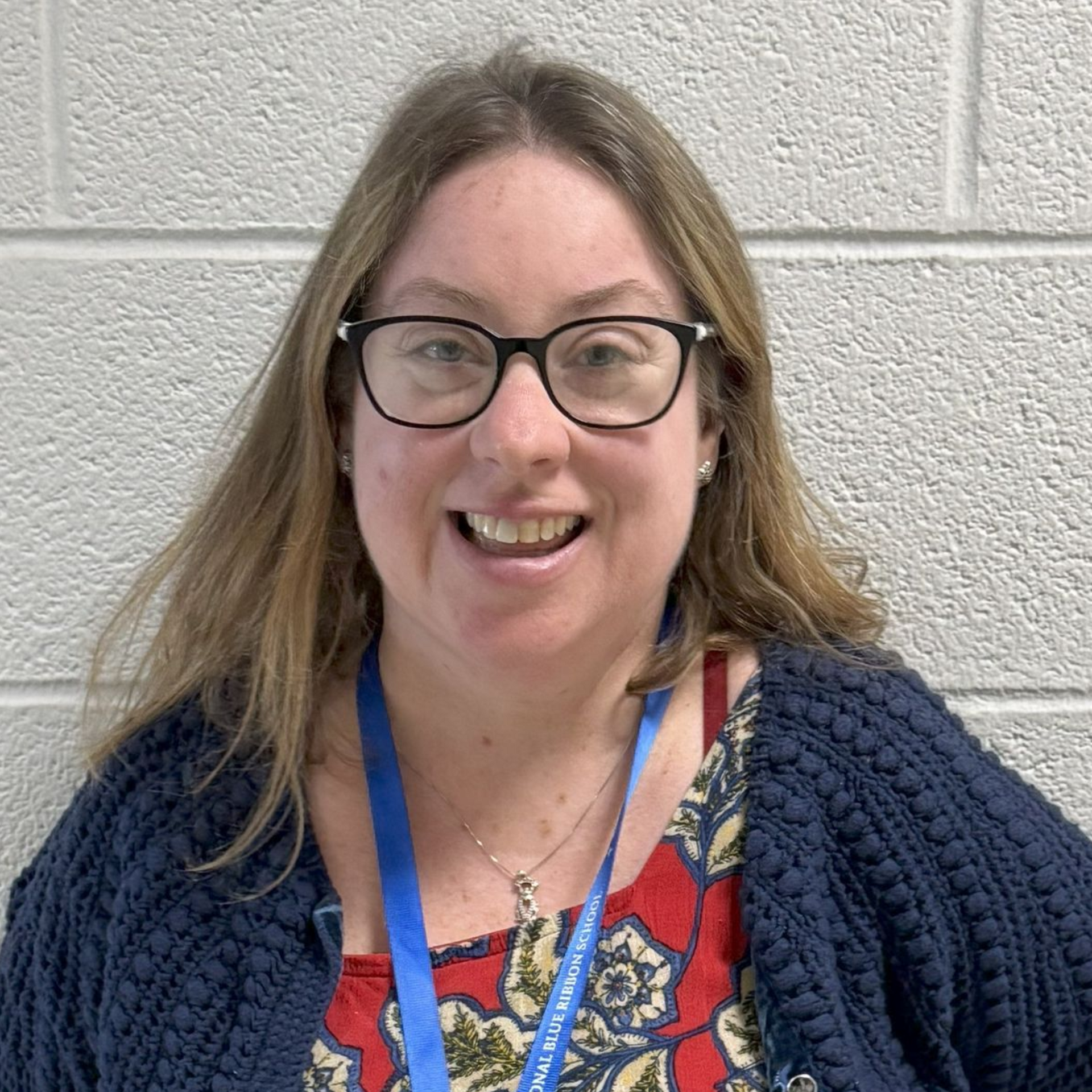 A woman wearing a lanyard around her neck is smiling for the camera.