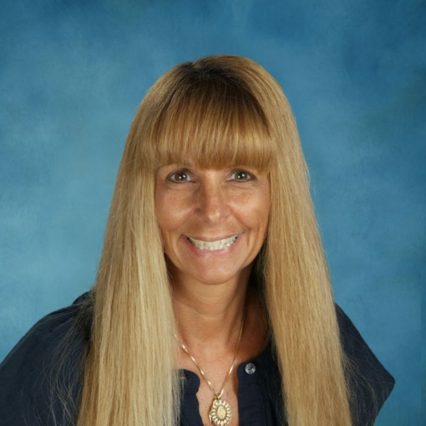 A woman wearing a leopard print shirt and a yellow lanyard smiles for the camera