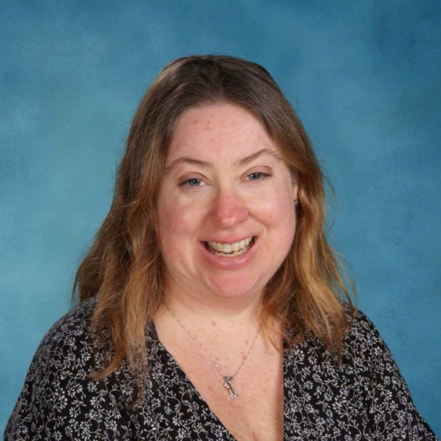 A woman wearing a lanyard around her neck is smiling for the camera.