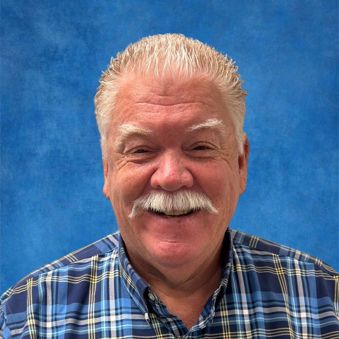 A woman is smiling for a picture in front of a blue background.