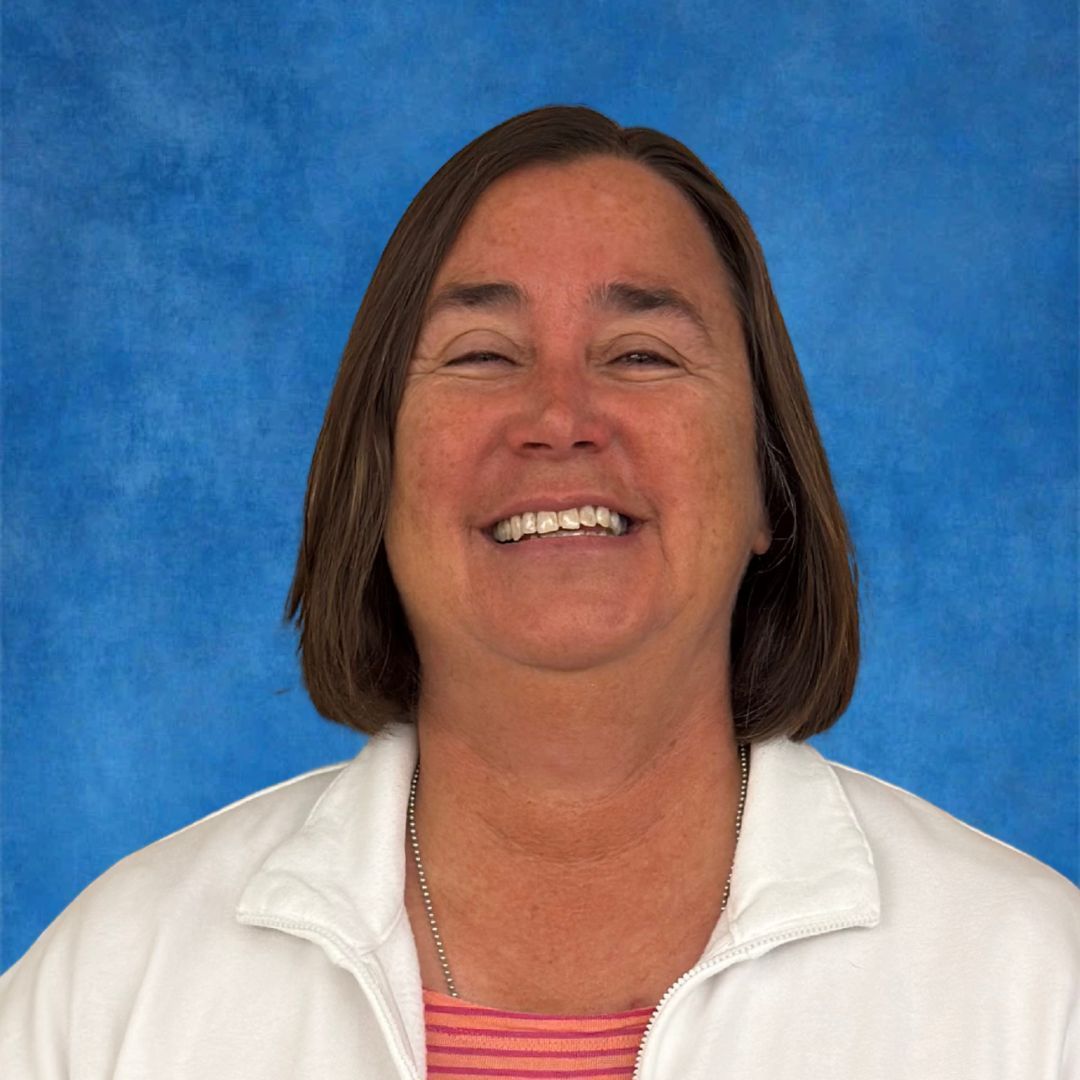 A woman is smiling for the camera while wearing a lanyard around her neck.
