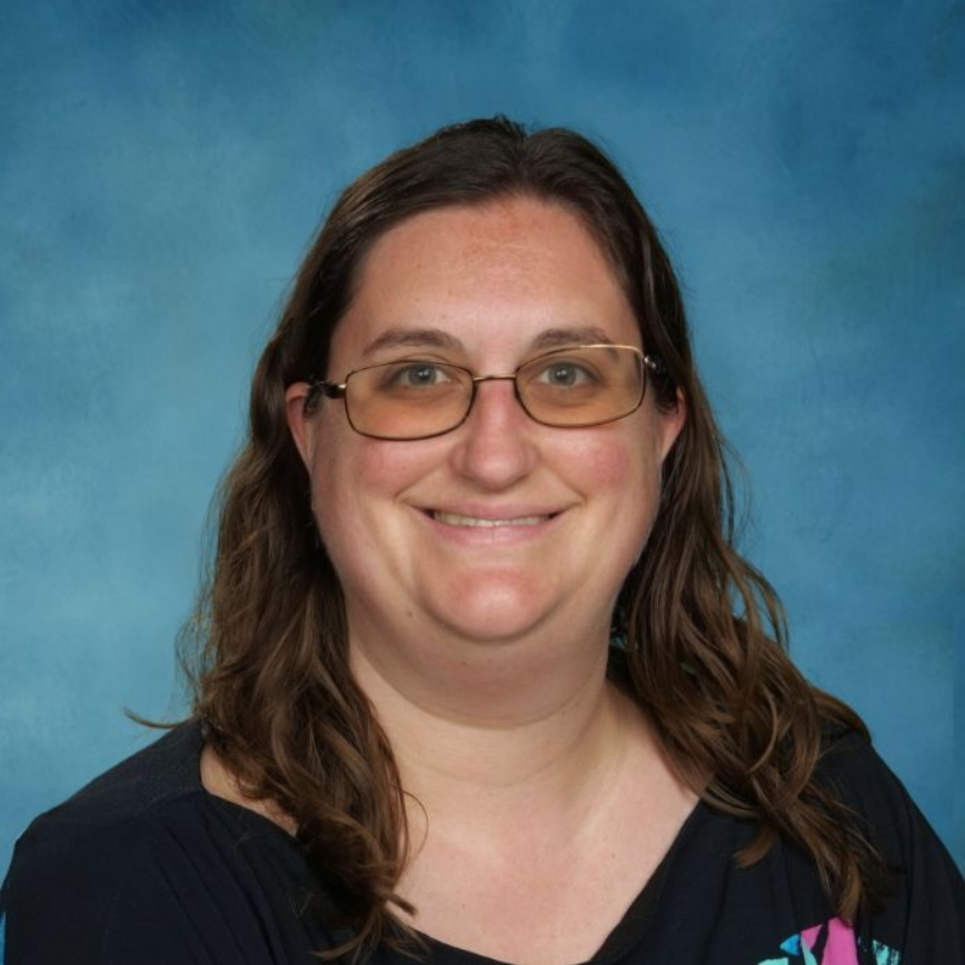 A woman wearing glasses and a green striped shirt is smiling.