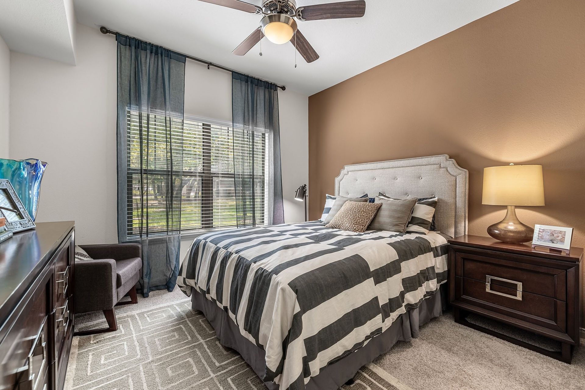 the master bedroom has a large window and a comfy bed