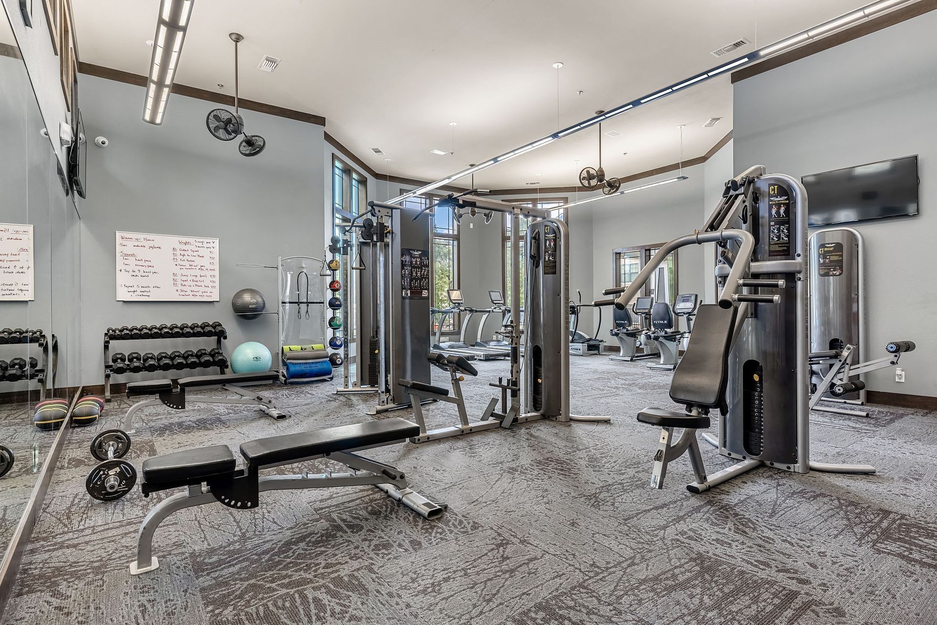 a gym with weights and cardio equipment and a tv
