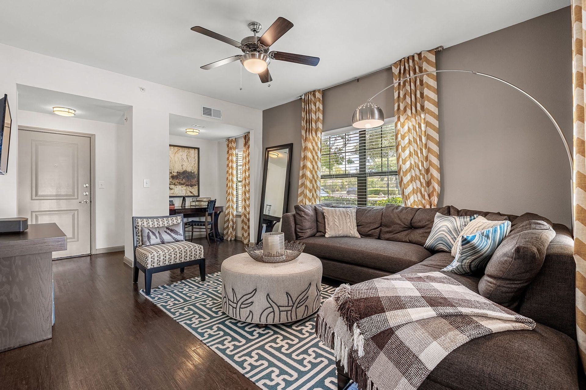 a living room with a large couch and a ceiling fan