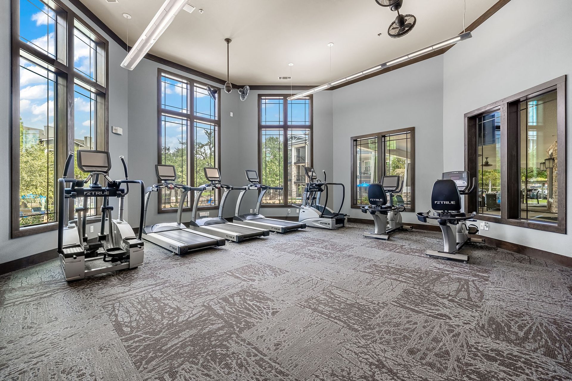 the gym with treadmills and windows at the estates apartments