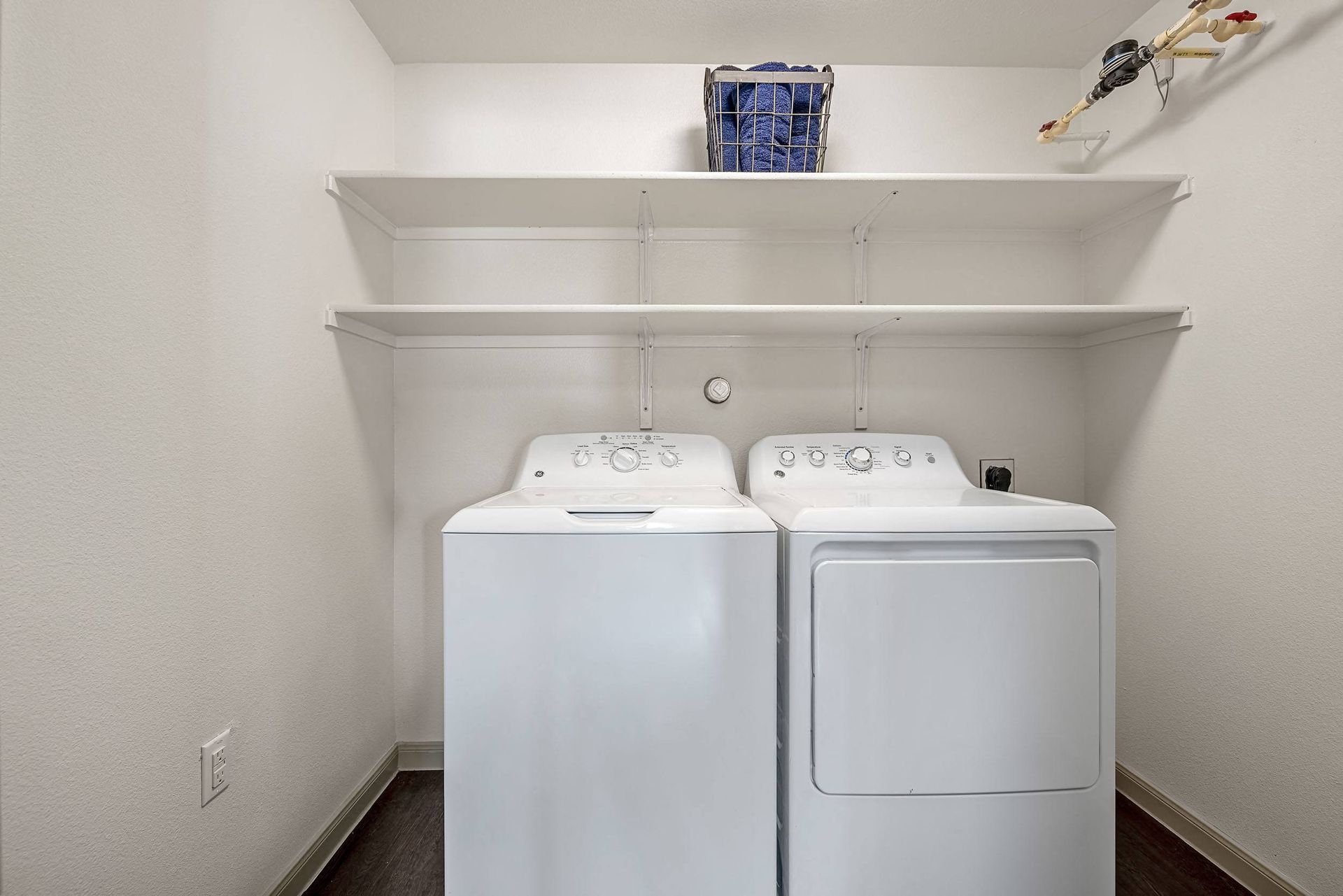 a washer and dryer in a white laundry room with shelves
