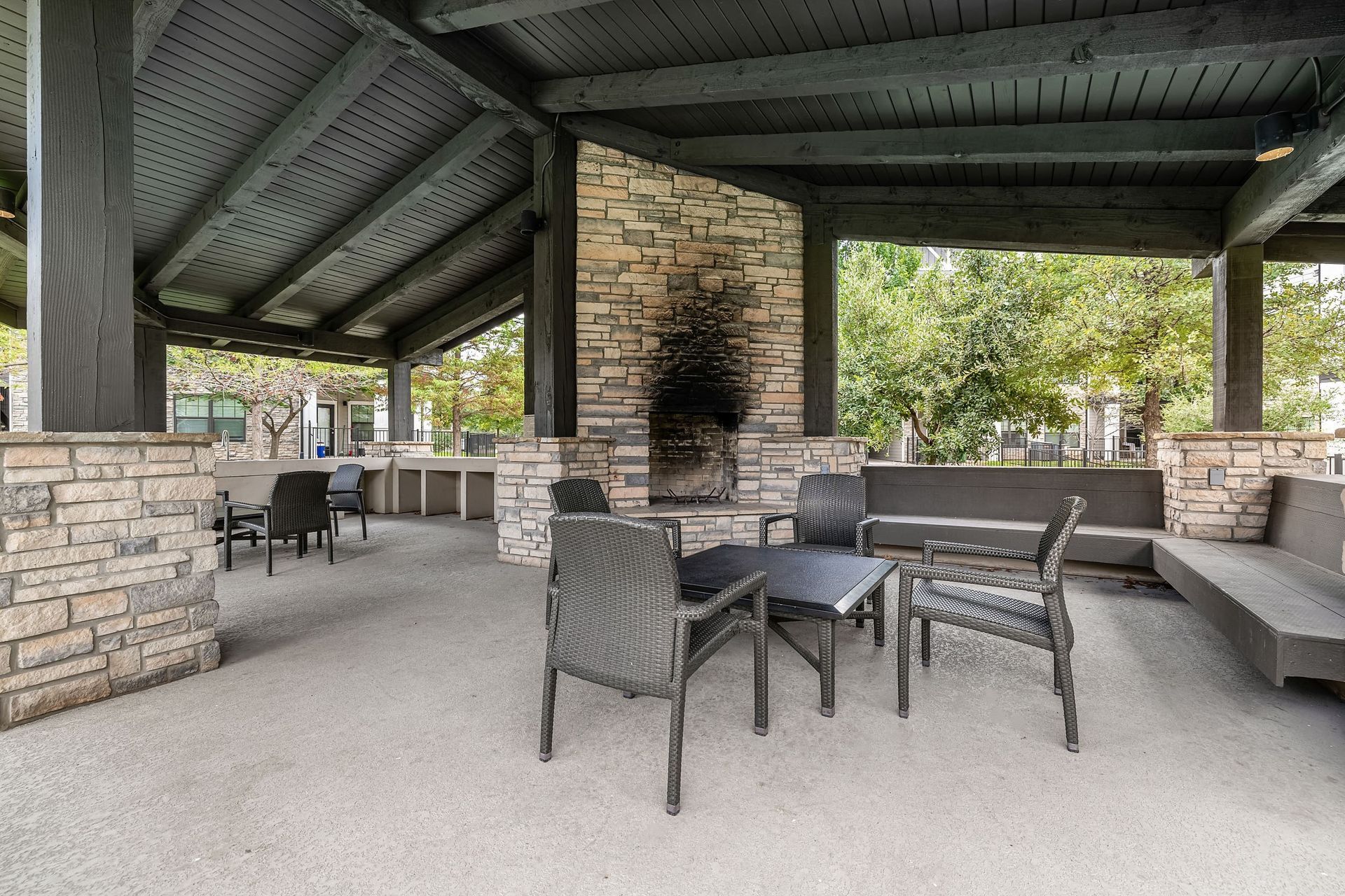 a covered patio with tables and chairs and a fireplace