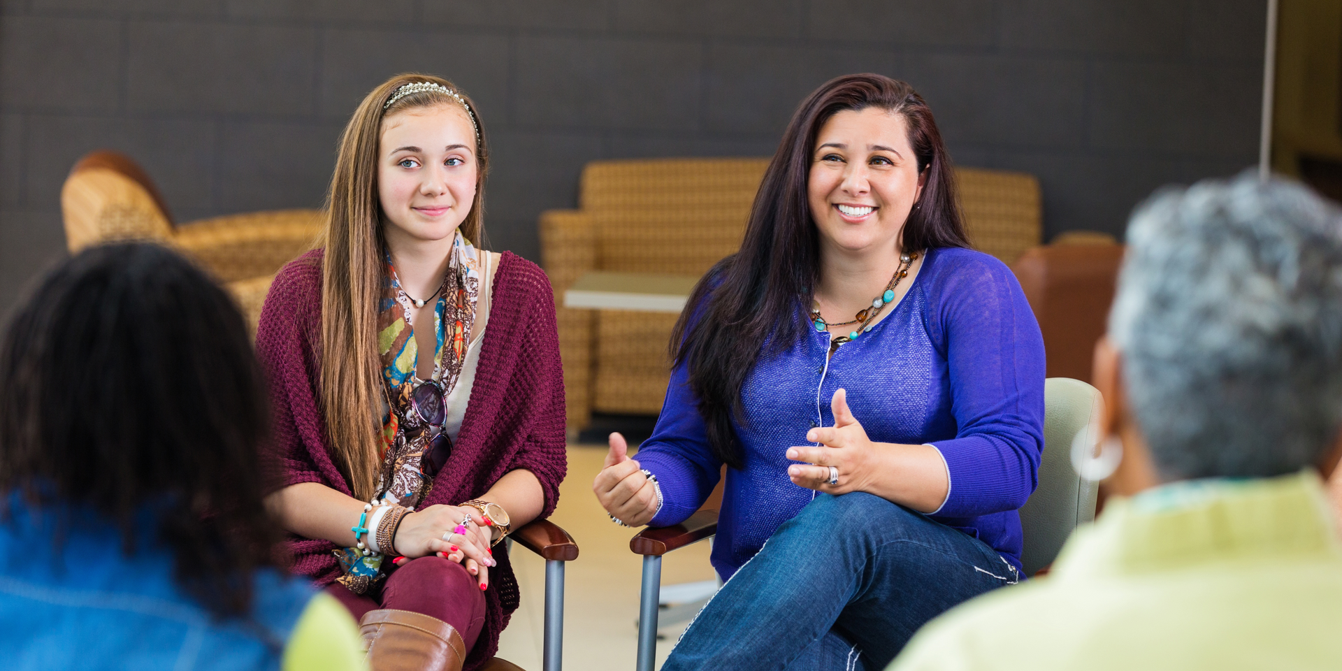 Two people are in a discussion circle, one in a purple shirt gestures, the other looks on.