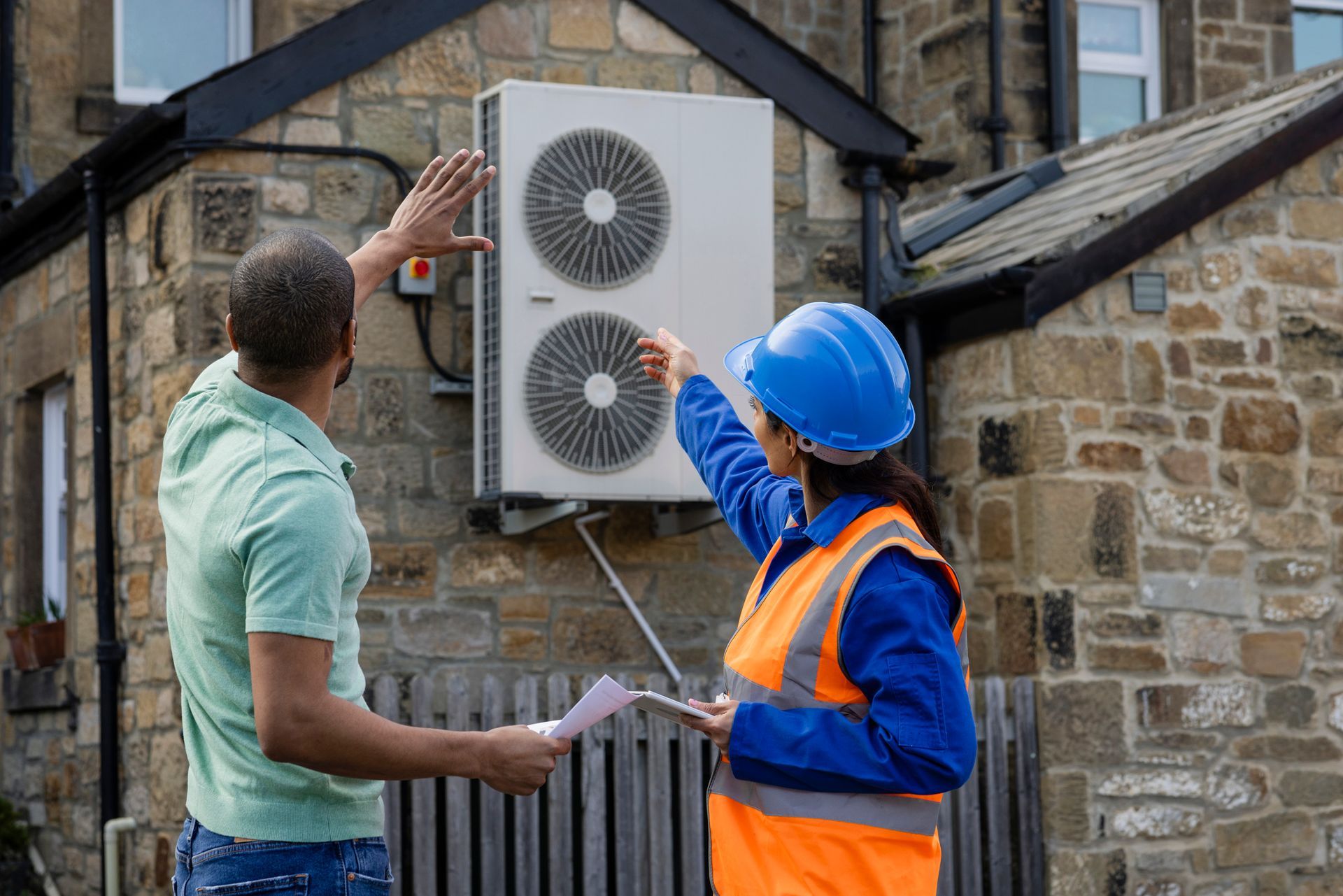 An air source heat pump on the side of a home being installed.