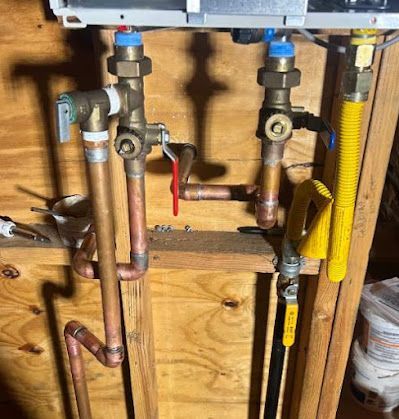 A bunch of pipes are connected to a boiler in a wooden room.