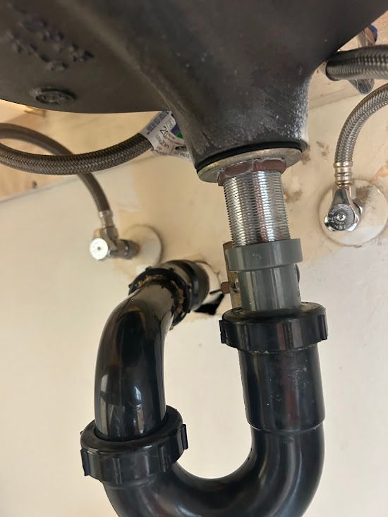 A close up of a sink drain with a hose attached to it.