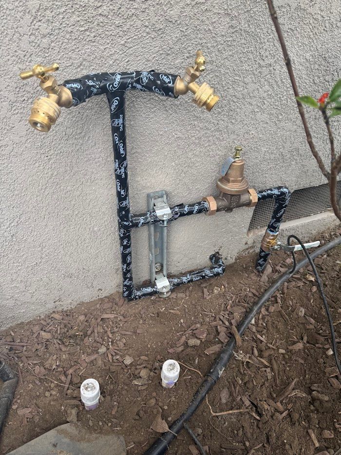 A faucet is sitting on the ground next to a wall.