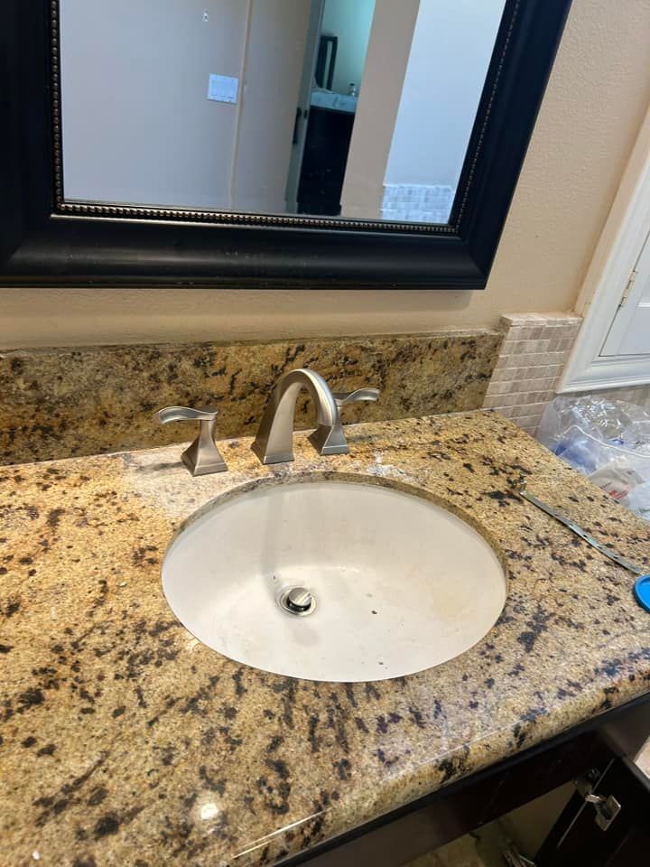 A bathroom sink with a mirror and granite counter top.