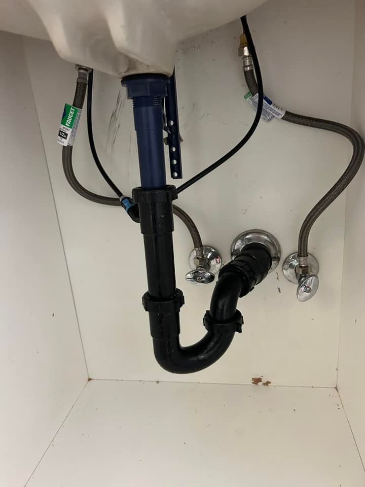 A bathroom sink with a black pipe underneath it.